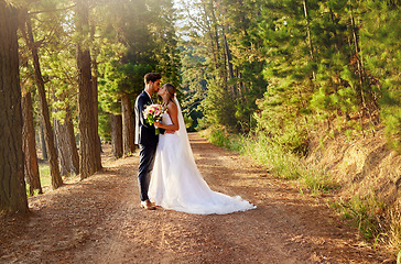 Image showing Wedding, married and couple kiss in forest, garden and nature for celebration of love, care and commitment. Bride, groom and kissing in park for romance, bridal event and celebrate marriage ceremony