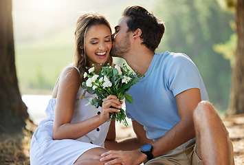 Image showing Man kiss woman, picnic with flowers in park with happy couple in nature, love with bonding and relax outdoor. Commitment, trust and relationship, people smile with summer and holiday with travel