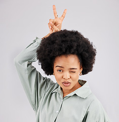 Image showing Goofy, happy woman and portrait with a wink, pout and bunny ears hand sign in a studio. Isolated, grey background and peace emoji hands of a female model feeling funny with fun comedy and joke