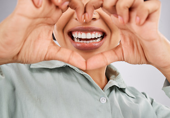 Image showing Love, smile and hands of a black woman with a heart isolated on a studio background. Happy, mouth and closeup of an African girl showing a shape for dental care, oral hygiene and teeth whitening