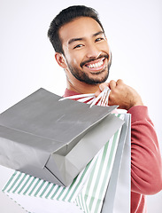 Image showing Portrait, retail and Asian man with shopping bags, smile and discount isolated against a white studio background. Face, Japanese male shopper and customer with parcels, package and purchase with joy