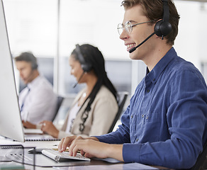 Image showing Man, call center and typing on computer, smile in office and working on customer service in workplace. Telemarketing, desktop and happiness of person, male sales agent or consultant consulting online