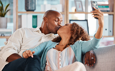 Image showing Couple, selfie and kiss on sofa in home living room, bonding or having fun together. Interracial, romantic picture and black man and woman taking photo while kissing for love, memory or social media.