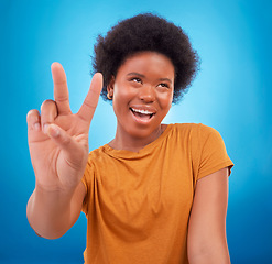 Image showing Peace sign closeup, black woman hand and happiness with a young female smile. Isolated, blue background and v hands gesture of a happy African model with a afro and beauty feeling cool and fun