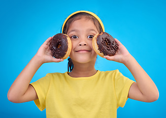 Image showing Donut, happy and smile with portrait of girl in studio for junk food, sugar and happiness. Snack, cake and cute with face of child and dessert for eating, diet and chocolate on blue background