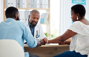 Image showing Doctor, black couple and holding hands in consultation clinic, support and comfort. Healthcare, obstetrician and man and woman talking with medical professional for advice, fertility treatment or ivf