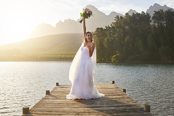 Image showing Wedding, bouquet and celebration with a bride on a pier over a lake in nature after a marriage ceremony. Happy, smile and flowers with a woman celebrating being married in the tradition of matrimony