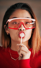 Image showing Portrait, fashion and woman with lollipop, glasses and confidence with stylish outfit, edgy and trendy. Face, female and lady with sweets, candy and funky eyewear with cool clothes and creativity