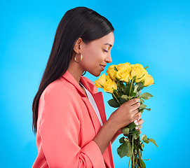 Image showing Smell, flowers and bouquet with woman in studio for gift, satisfaction and spring. Relax, happy and floral present with female and roses isolated on blue background for aroma, natural and products