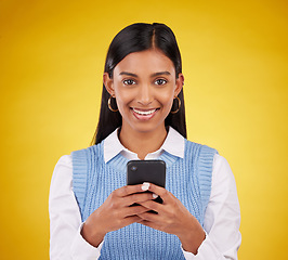 Image showing Smile, phone and portrait of woman in studio space typing message or email on yellow background. Technology, communication and happy face of Indian gen z model checking social media or online content