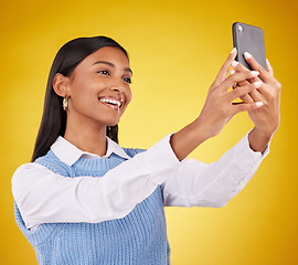 Image showing Happy, smile and selfie with woman in studio for social media, technology and internet post. App, online and picture with female on yellow background for happiness, connection and photography