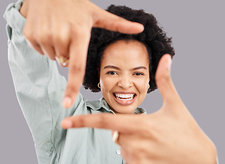 Image showing Happy, portrait and woman with hand frame in a studio posing with a positive face expression. Happiness, smile and headshot of an African female model with a finger border isolated by gray background