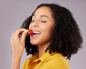 Image showing Woman, face and eating strawberry for natural nutrition, dieting or healthy food against a gray studio background. Happy female smiling and enjoying tasty organic fruit for health, diet or wellness