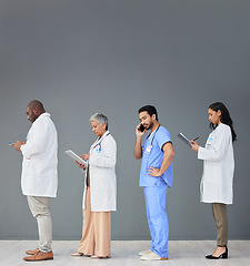 Image showing Doctors standing in a row isolated on wall background with tablet, phone call and medical paperwork for hospital. Healthcare people or nurse technology in waiting room for clinic or hiring research