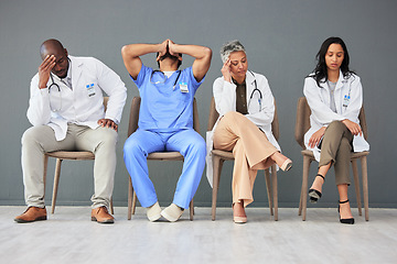 Image showing Exhausted, tired and doctors waiting in the hospital with frustration, sad and burnout. Upset, professional and team of healthcare workers sitting in a line in a hallway for meeting in medical clinic