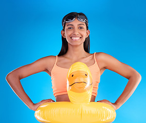 Image showing Happy, pool float and portrait of woman in studio for summer, swimming and holiday. Smile, happiness and beach vacation with female and duck inflatable on blue background safety, playful and funny