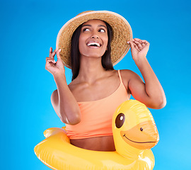 Image showing Thinking, hat and rubber duck with a woman on a blue background in studio ready for summer swimming. Happy, travel and vacation with an attractive young female looking excited to relax or swim