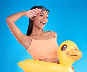 Image showing Portrait, smile and salute with a swimmer woman in studio on. a blue background wearing goggles on her head. Happy, hand gesture and swimming with an attractive young female excited to swim in summer