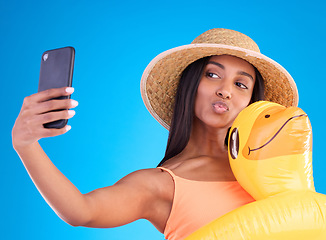 Image showing Happy woman, selfie and swimming vacation for social media or profile picture with inflatable duck against a blue studio background. Excited female model in summer swimwear for photo, travel or trip