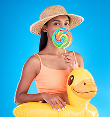 Image showing Portrait, lollipop and rubber duck with a woman on a blue background in studio ready for summer swimming. Happy, travel and vacation with an attractive young female looking excited to relax or swim