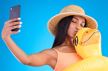 Image showing Happy woman, selfie and swimming travel for social media or profile picture with inflatable duck against a blue studio background. Excited female model in summer swimwear for photo, vacation or trip