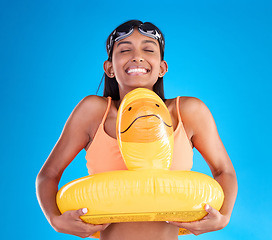 Image showing Smile, goggles and rubber duck with a woman on a blue background in studio ready for summer swimming. Happy, travel and vacation with an attractive young female feeling excited to relax or swim