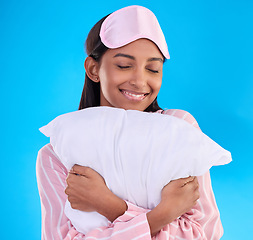 Image showing Bedtime, happy and a woman hugging a pillow isolated on a blue background in a studio. Smile, comfy and a girl ready for sleep, nap or slumber in pyjamas for comfort and coziness on a backdrop