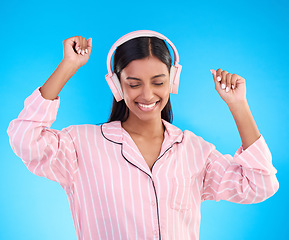 Image showing Happy, dance and woman in pajamas, headphones and cheerful on a blue studio background. Female, joyful and lady with headset, waking up and dancing with sounds, streaming music and songs for movement