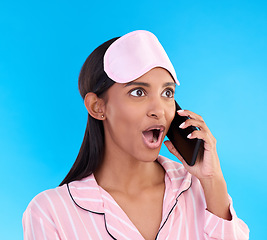 Image showing Phone call, shock and woman in pajamas in a studio with shocking, winning or good news. Surprise, happy and Indian female model on a mobile conversation with a wtf, omg or wow face by blue background