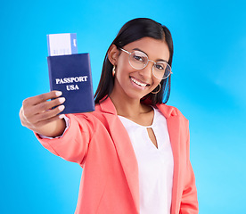 Image showing Happy woman, passport or ticket for travel, flight or USA documents against a blue studio background. Portrait of female business traveler smile holding international boarding pass or booking trip