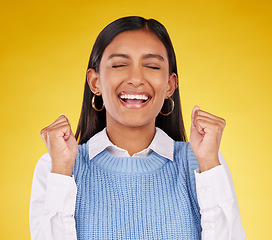 Image showing Celebration, winner and fist pump with woman in studio for success, excited and happy cheering. Wow, yes and achievement with female on yellow background for victory, promotion and good news