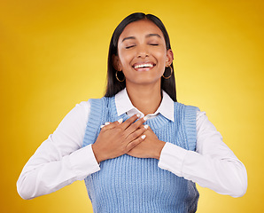 Image showing Gratitude, happy and young woman in a studio with her hand on her chest for a grateful expression. Happiness, smile and Indian female model with a thankful hand gesture isolated by yellow background.