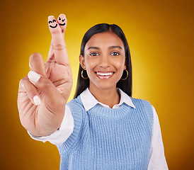 Image showing Smiley face, fingers crossed and portrait of Indian woman in studio with drawing for hand sign, symbol and luck. Emoji mockup, yellow background and happy girl smile for wish, hope and lucky gesture