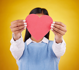 Image showing Cover, paper and heart with woman in studio for love, support and romance. Valentines day, kindness and date with female hiding with symbol on yellow background for health, happiness and hope mockup