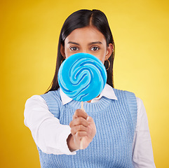 Image showing Hide, lollipop and candy with portrait of woman in studio for sweets, snack and food. Treats, dessert and sugar confectionery with female isolated on yellow background for diet, eating and cover