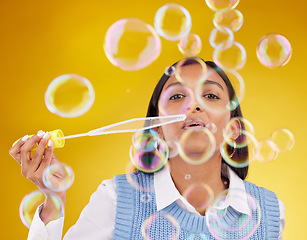 Image showing Portrait, fun and woman blowing bubbles, positive attitude and cheerful against a studio background. Face, female and lady with soap bubble, excitement and joyful with wellness, break and playful