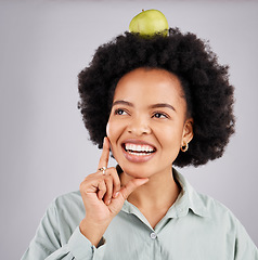 Image showing Thinking, apple on head and black woman with happiness, wellness and health on a grey studio background. African American female, fruit and lady with ideas, planning diet and wellness with body care