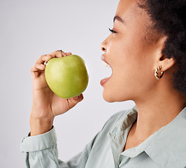 Image showing Apple, health and black woman in studio eating for nutrition, wellness and healthy snack. Food, diet and face profile of girl eat green fruit for detox, vitamins and weight loss on white background