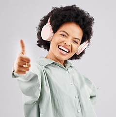 Image showing Portrait, thumbs up and black woman with headphones in studio isolated on a white background. Success, funny and person with hand gesture, emoji or winning, agreement or like while streaming music.