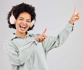 Image showing Portrait, music headphones and black woman pointing up in studio isolated on a white background mockup or advertising space. Singer, radio and happiness of person listening to audio, sound or podcast