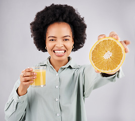 Image showing Portrait, orange and juice with a woman, happy in studio on a gray background for health or vitamin c. Face, drink and fruit with a young female drinking a fresh beverage in a glass for nutrition