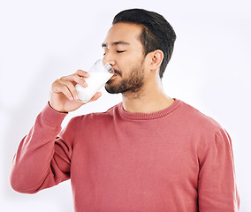 Image showing Man drinking glass of milk in studio, white background and backdrop for healthy dairy, smoothies and diet. Male model, cup and calcium of smoothie, vanilla milkshake and nutrition of protein drink