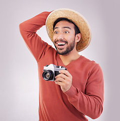 Image showing Wow, camera and travel, shocked man in studio with hat on holiday, adventure and fun on white background. Smile, surprise and happy person on vacation, happiness and shock for photographer on journey