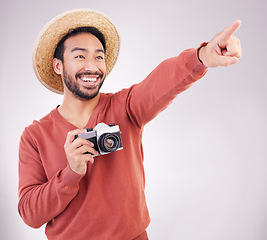 Image showing Travel, camera and excited man pointing at view in studio on holiday with adventure, fun and white background. Smile, discovery and happy tourist on vacation, photographer on journey with happiness.