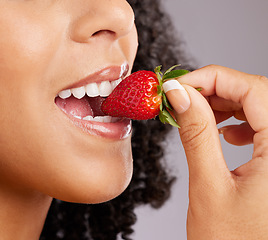 Image showing Woman, mouth and eating strawberry for natural nutrition, dieting or healthy food against a gray studio background. Closeup of female lips enjoying tasty organic fruit for health, diet or wellness