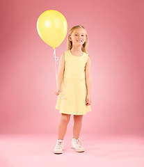 Image showing Girl, child and portrait with a balloon in studio on a pink background with smile. Female kid model with happiness, creativity and yellow birthday party decoration in hand isolated on color and space