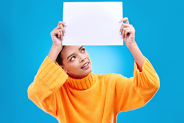 Image showing Poster, thinking and face of woman on blue background for announcement, news and information. Advertising, mockup studio and isolated happy girl with paper sign for brand, logo and marketing