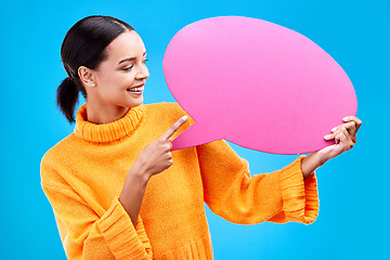 Image showing Speech bubble, smile and woman pointing to banner in studio for advertising on blue background. Happy, finger and female with poster, mockup and space for social media, announcement or billboard news