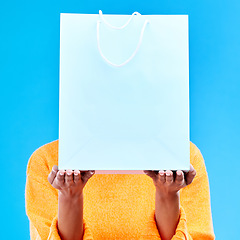 Image showing Shopping, bag and hands of woman on blue background for retail discount, deal and store promotion. Commerce mockup, fashion and girl holding package for advertising, sale news and purchase in studio