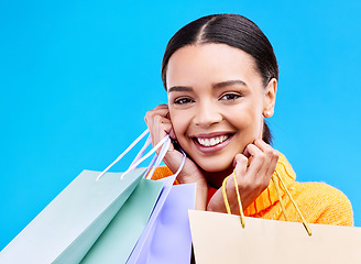 Image showing Shopping bags, studio and woman portrait with a smile and happiness from boutique sale. Happy, customer and female model with store bag and sales choice in isolated blue background with young person